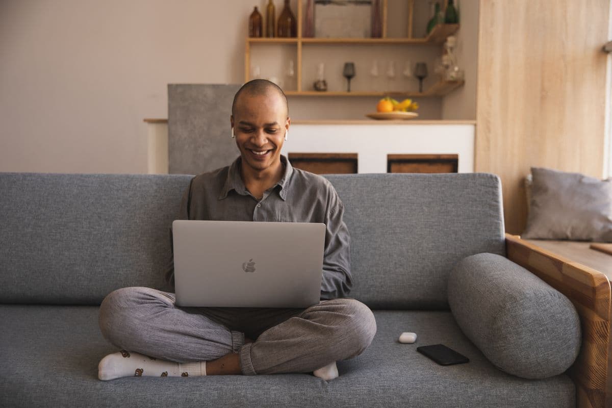 A self-employed man smiling while working on his laptop at home
