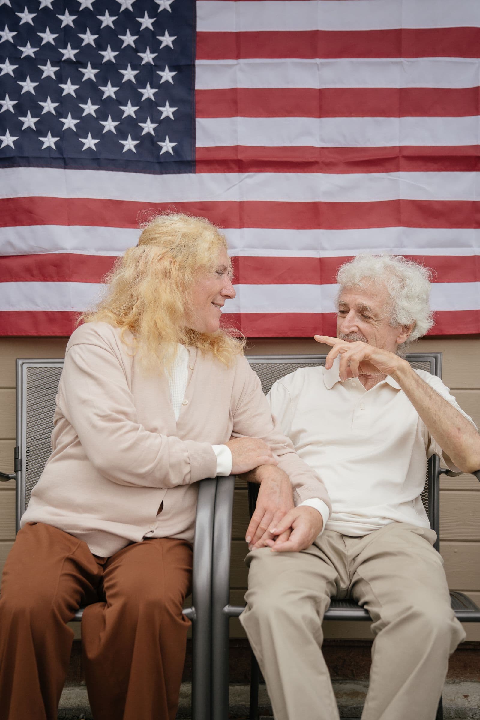 A retired couple sitting together in front of an American flag