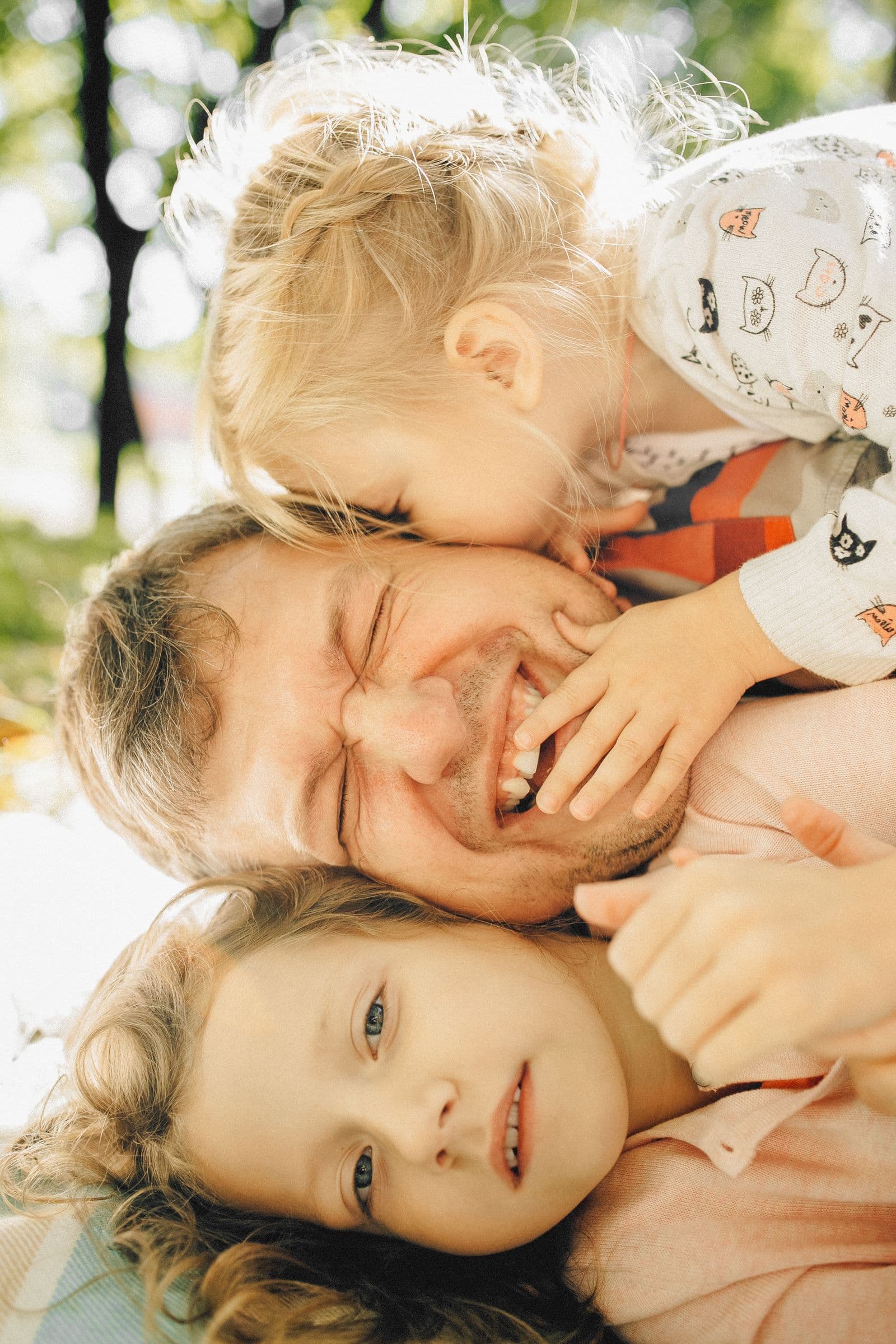 A dad laughing with his two kids piled on top of him